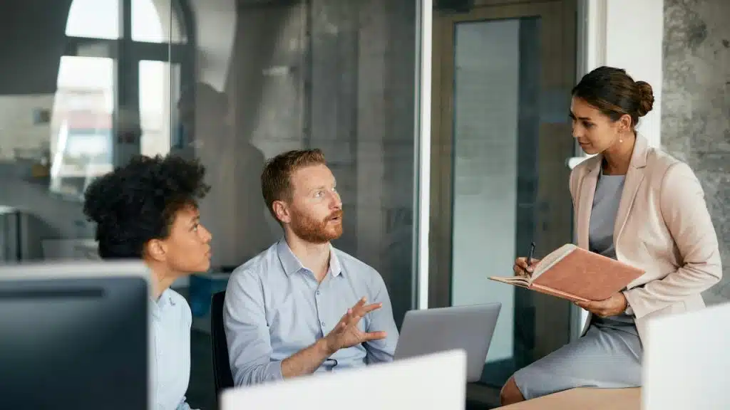 A group of coworkers engaged in discussion during an office meeting.