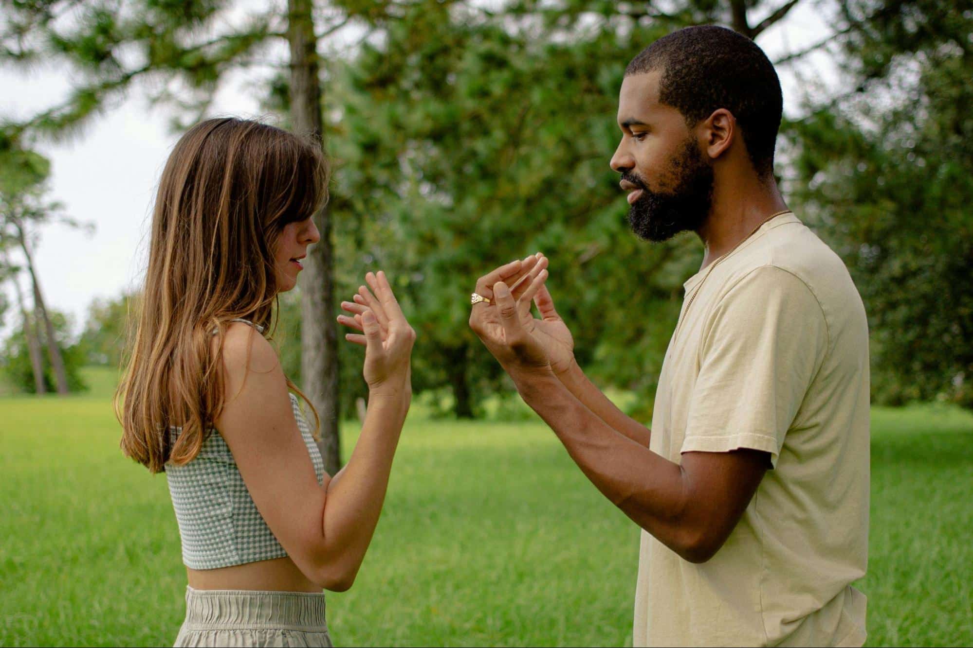 A man teaching a woman to copy him.