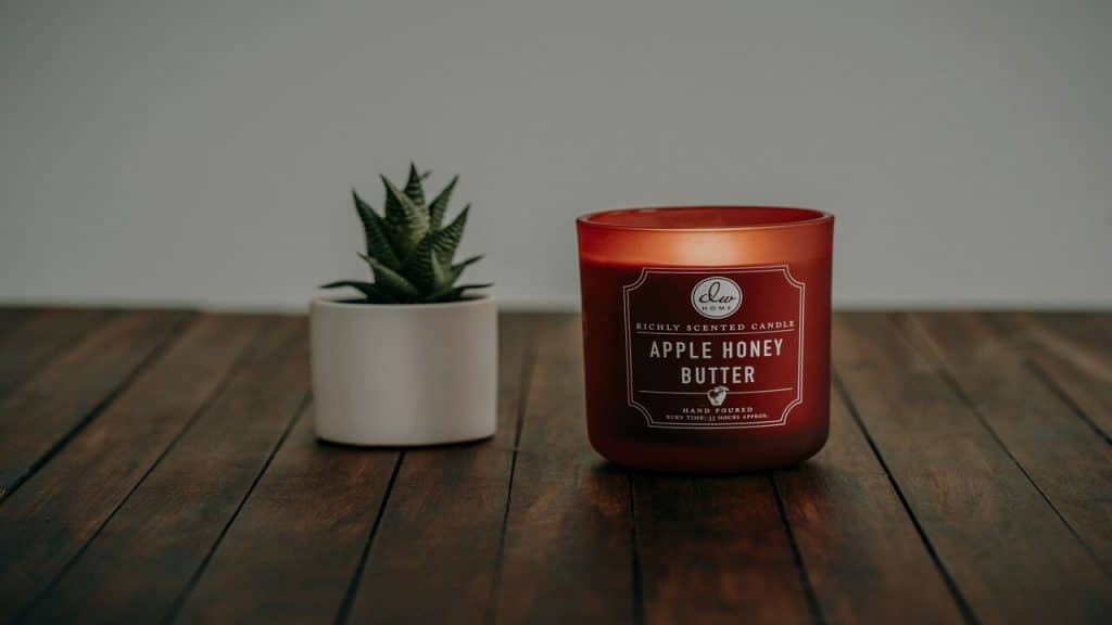 A scented candle beside a potted plant