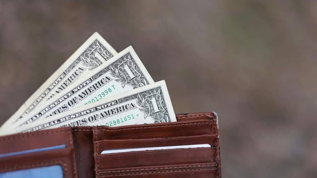 An open wallet holding three one‑dollar bills.