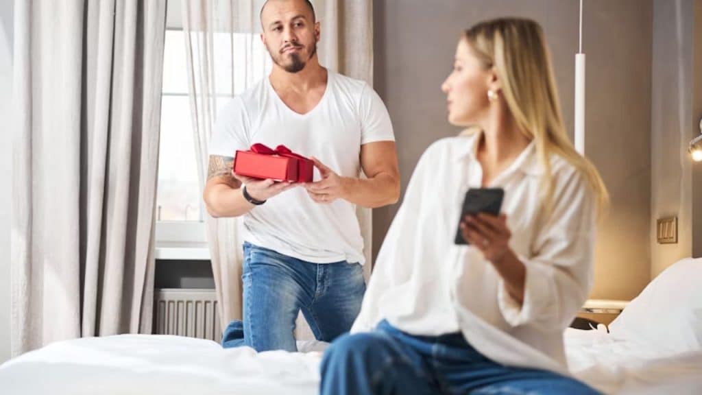 Man giving a gift or gesture while his partner seems distracted or not interested.