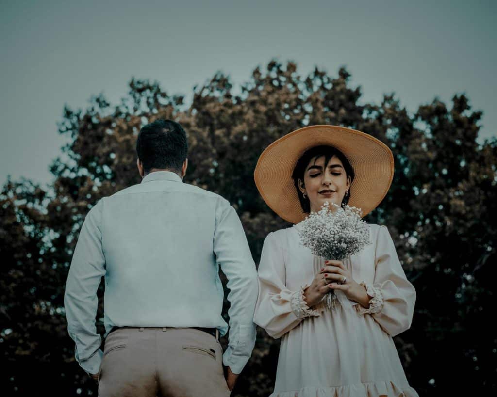 A woman holding a flower and a man beside her.
