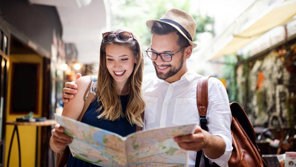 A smiling couple reading a city map in an outdoor alleyway.