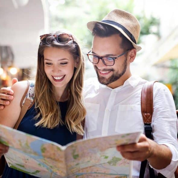 A smiling couple reading a city map in an outdoor alleyway.
