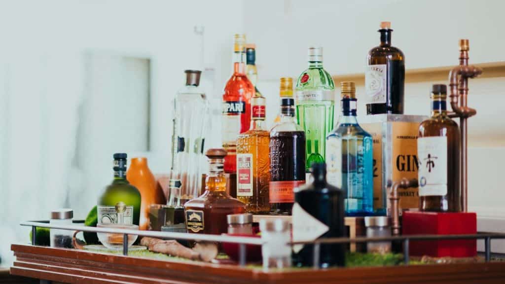 A variety of liquor bottles are arranged on a home bar setup.