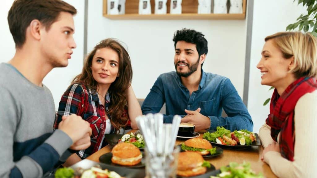 A group of friends chatting over burgers and salads at a table.