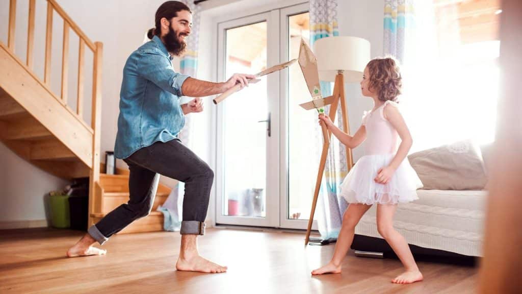A father sword-fighting his daughter with cardboard swords.