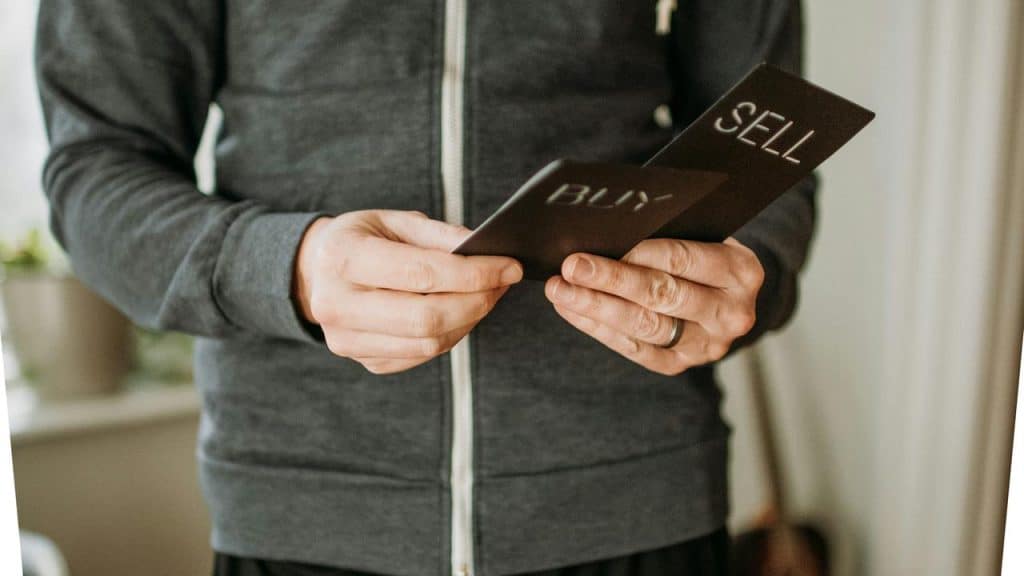 A person holding black cards labeled “BUY” and “SELL.”
