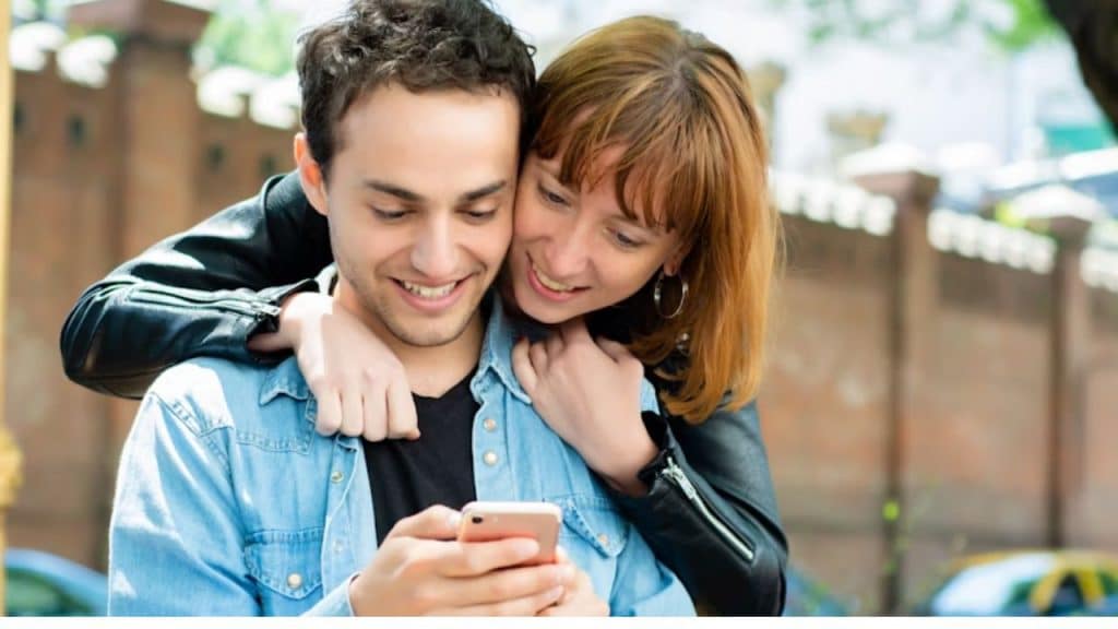 A couple having fun offline while one person scrolls through perfect social media photos