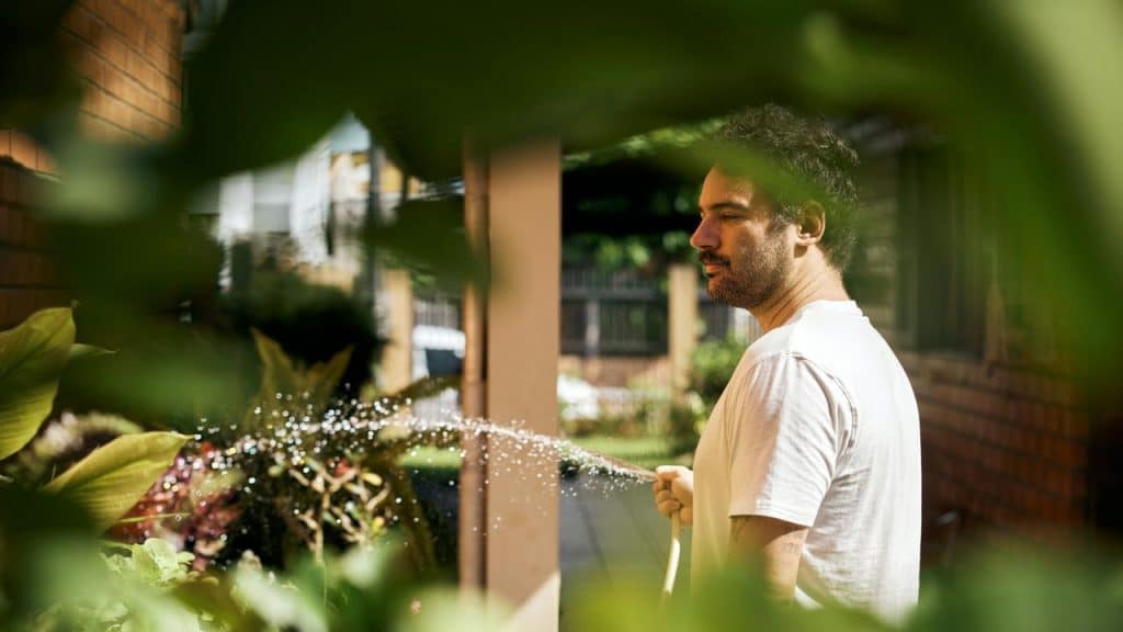 A man watering plants with a hose.