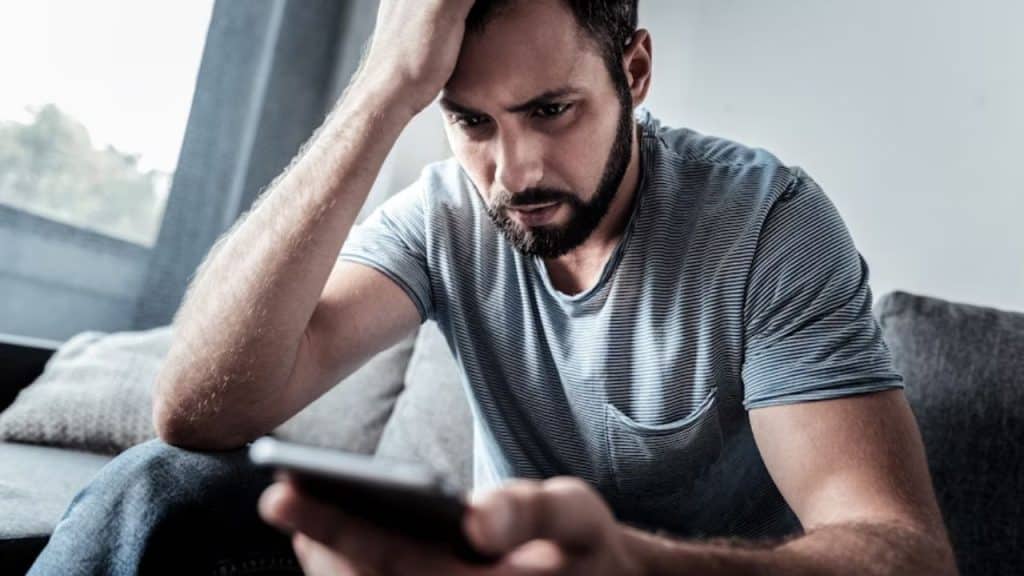 A man pausing while reading a comment thread, looking conflicted