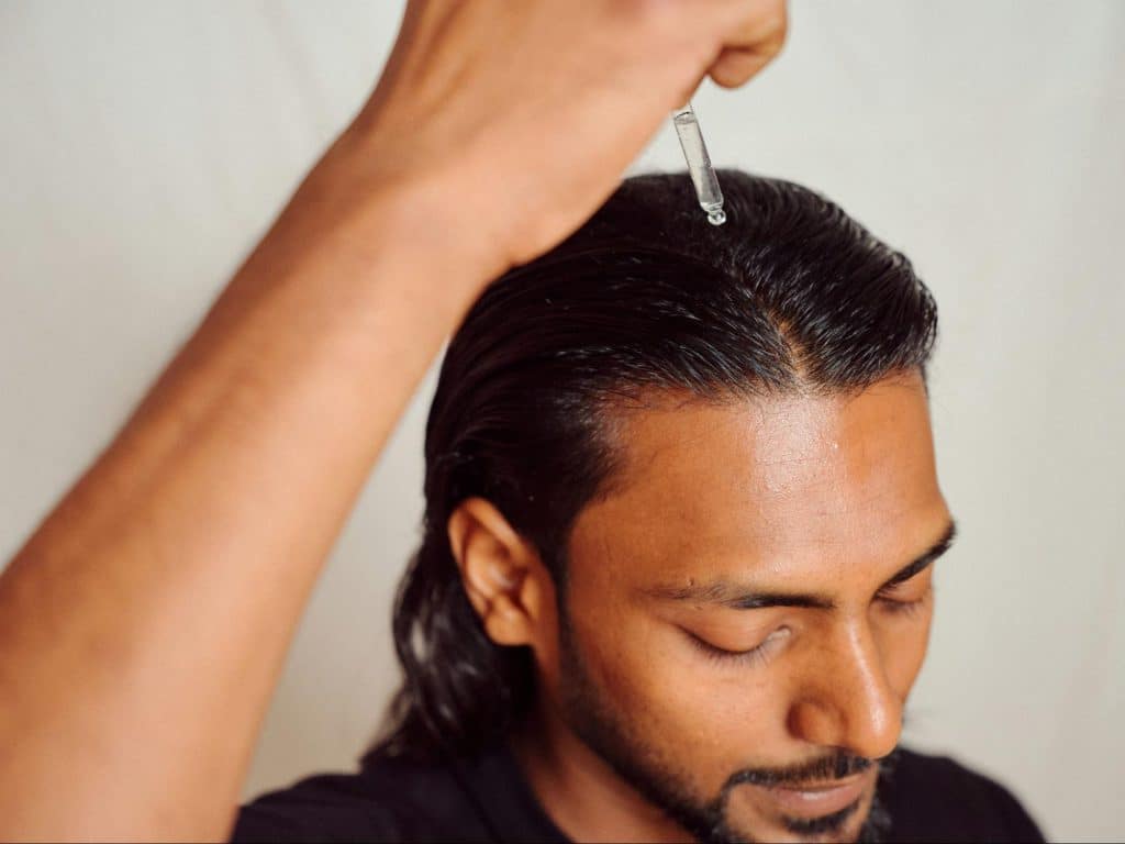 A man using a wax for hair.