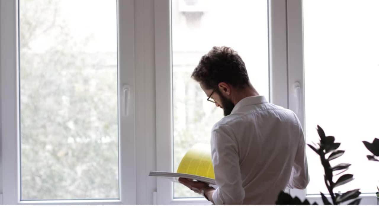 ALT Text: A man reading a book on emotional intelligence in a quiet room.