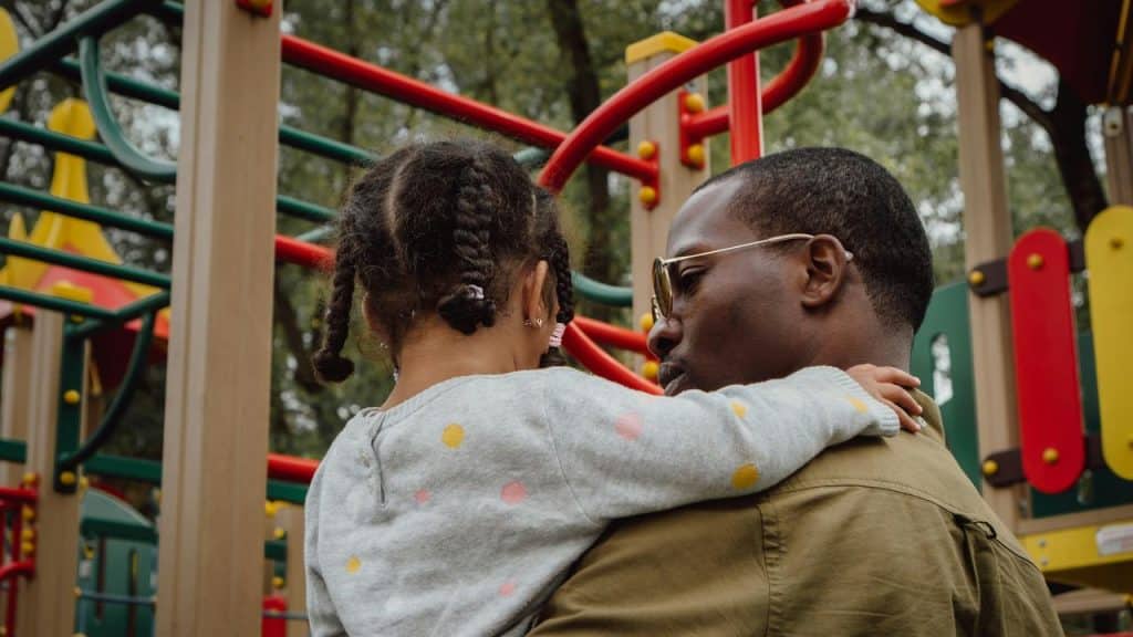A father holding his daughter at a playground.