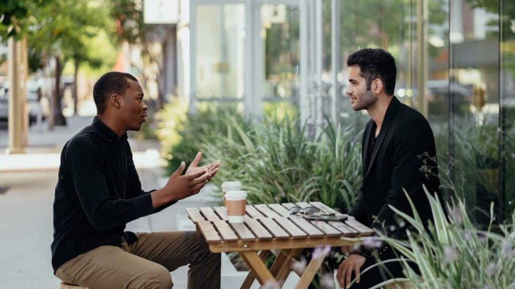 Man talking to a friend over coffee, both engaged and open