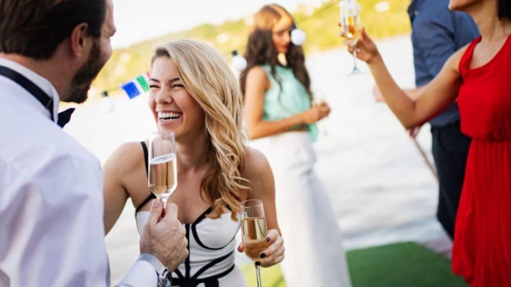 A man complimenting a woman at a social event with an open smile