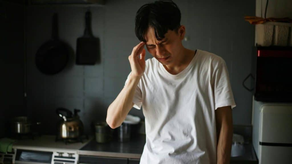 A man clutching his head in a kitchen.
