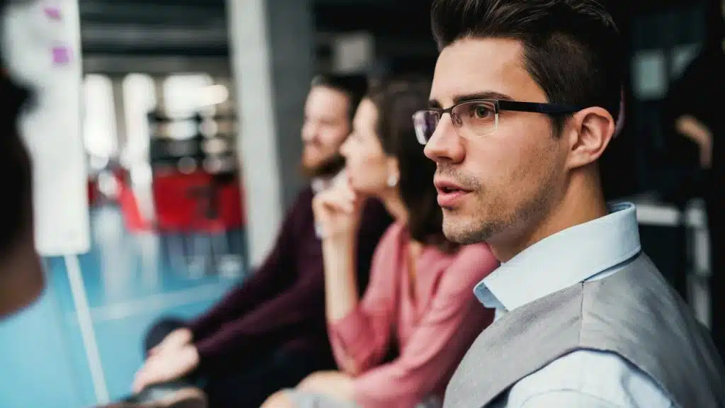 A man wearing glasses attentively listening during a meeting.