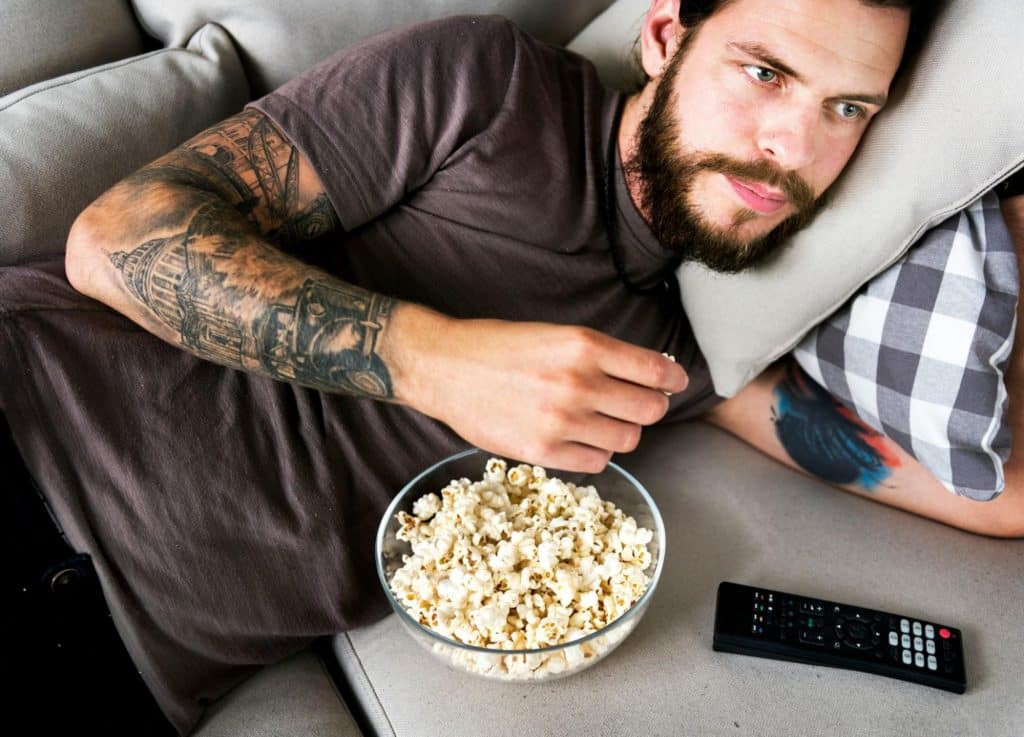A man watching a movie while eating a popcorn