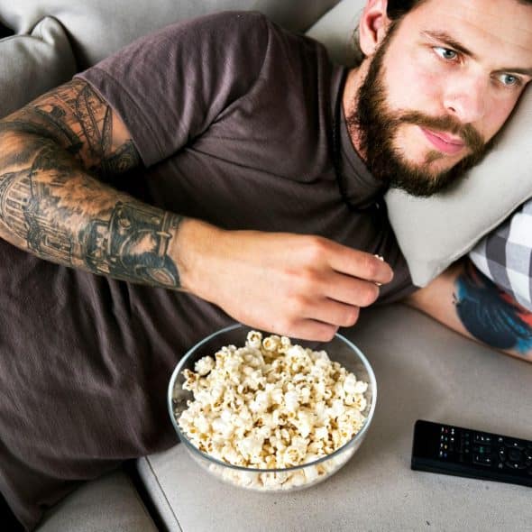 A man watching a movie while eating a popcorn