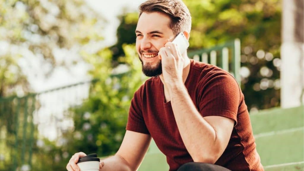 Confident man smiling while enjoying a relaxed moment outside.