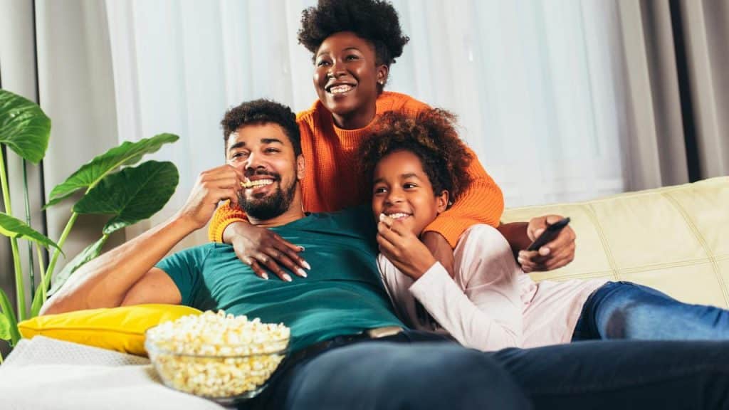 A family eating popcorn together on a couch.