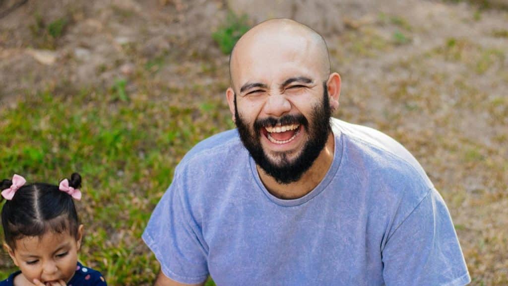 A laughing bearded man beside a child.