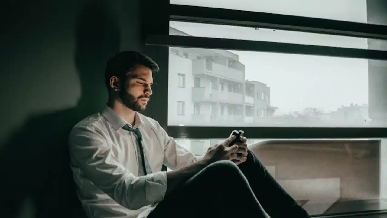 A man deleting a dating app on his phone while exhaling deeply.