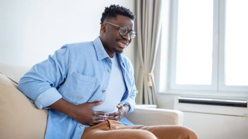 Man holding stomach in discomfort after a high protein meal.