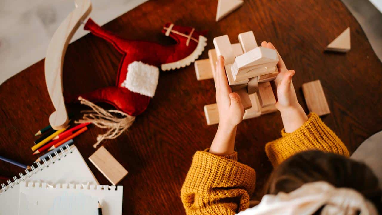 A child stacking wooden blocks on a table.