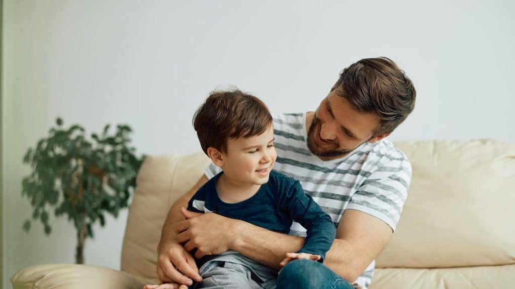 A father holding his son on a couch.