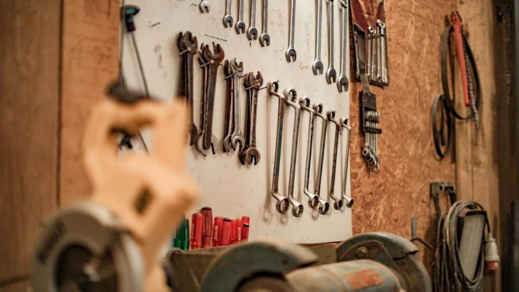 A row of metal wrenches hanging on a workshop board.
