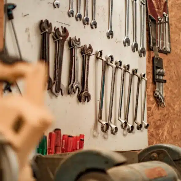 A row of metal wrenches hanging on a workshop board.