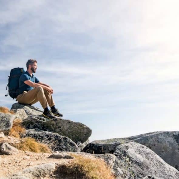 Man standing on a hilltop at sunrise with peaceful expression symbolizing personal growth