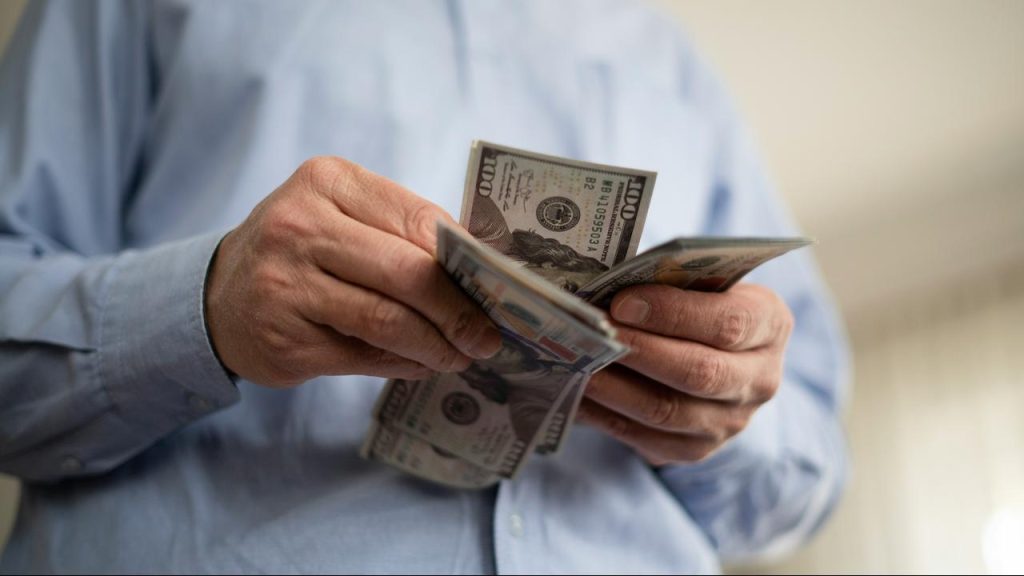 A person counting hundred‑dollar bills.