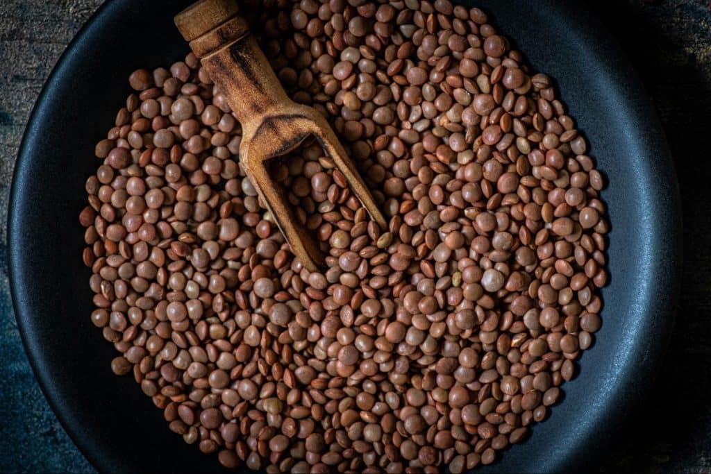 A picture of lentils with a wooden scoop.