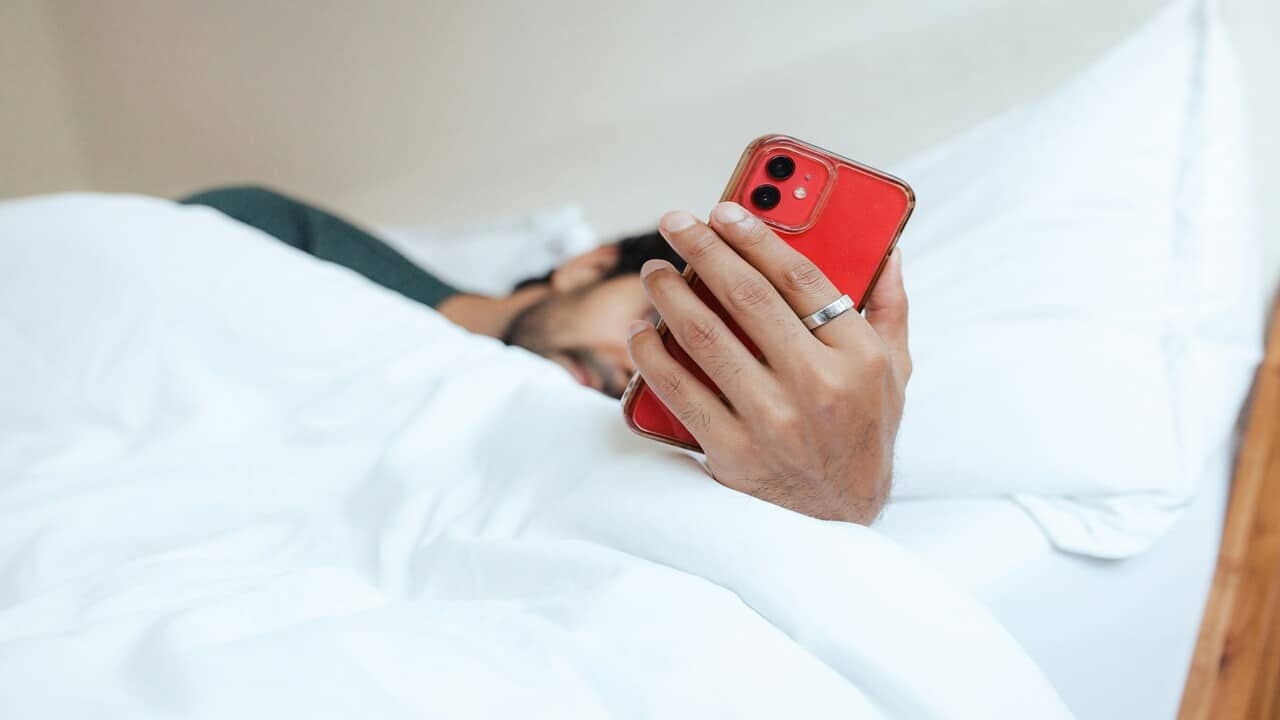 A man using his phone in bed.