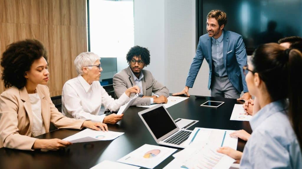 A diverse group of professionals are engaged in a meeting around a conference table.