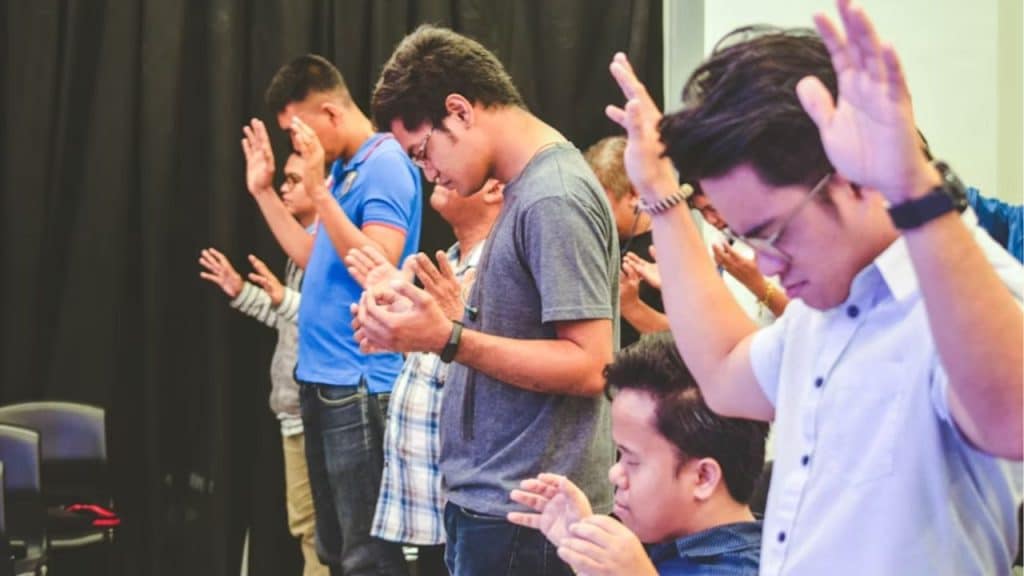 A group of men with their hands raised in what appears to be worship or prayer