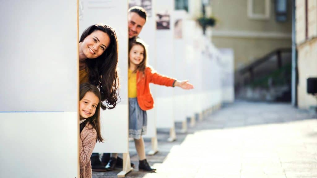 A family peeking around outdoor display panels.