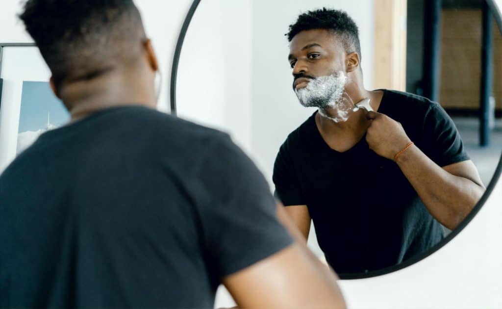 A man shaving his beard.