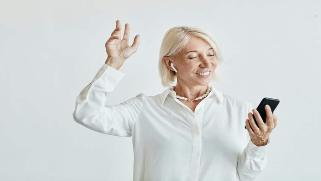 An older woman smiling while listening to music