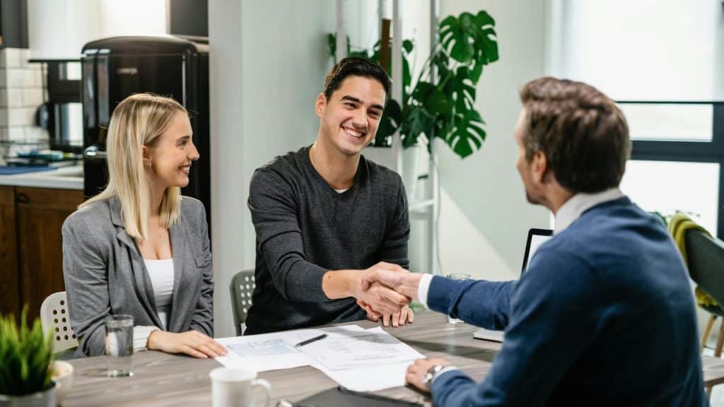 A couple shaking hands with an advisor across a desk.
