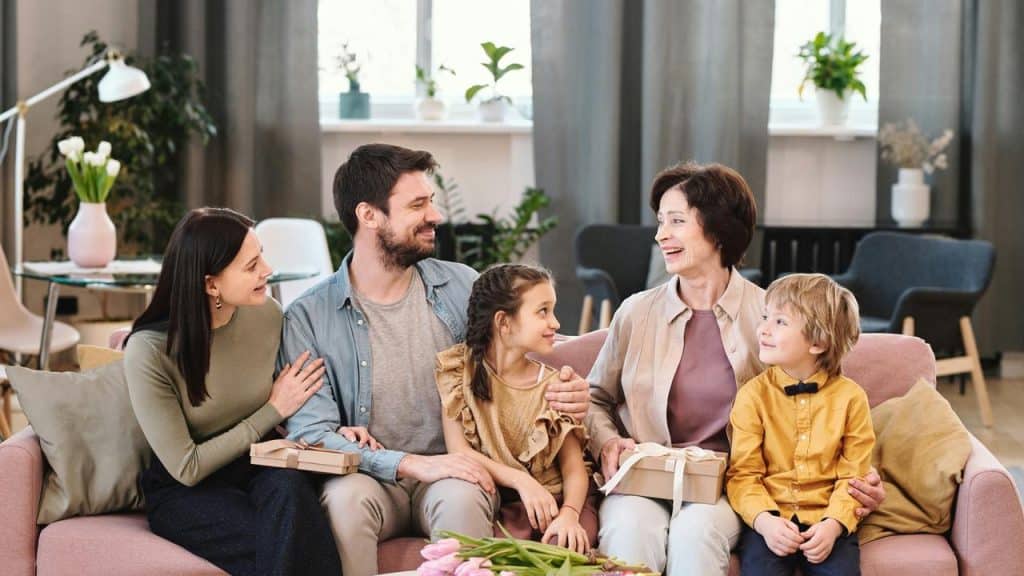 A family giving gifts to their grandmother on a couch.