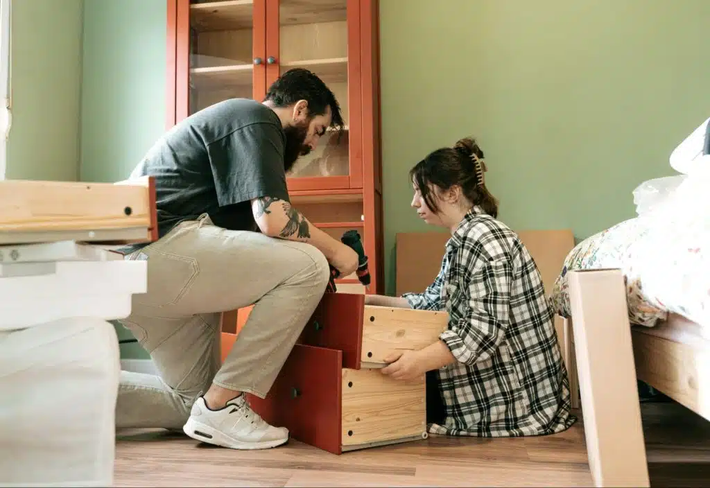 A man helping a woman fixing a cabinet.