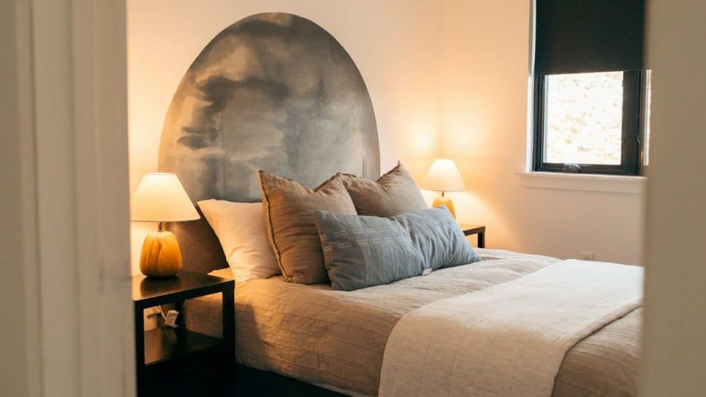 A cozy bedroom features a bed with soft bedding, pillows, and a unique headboard design.