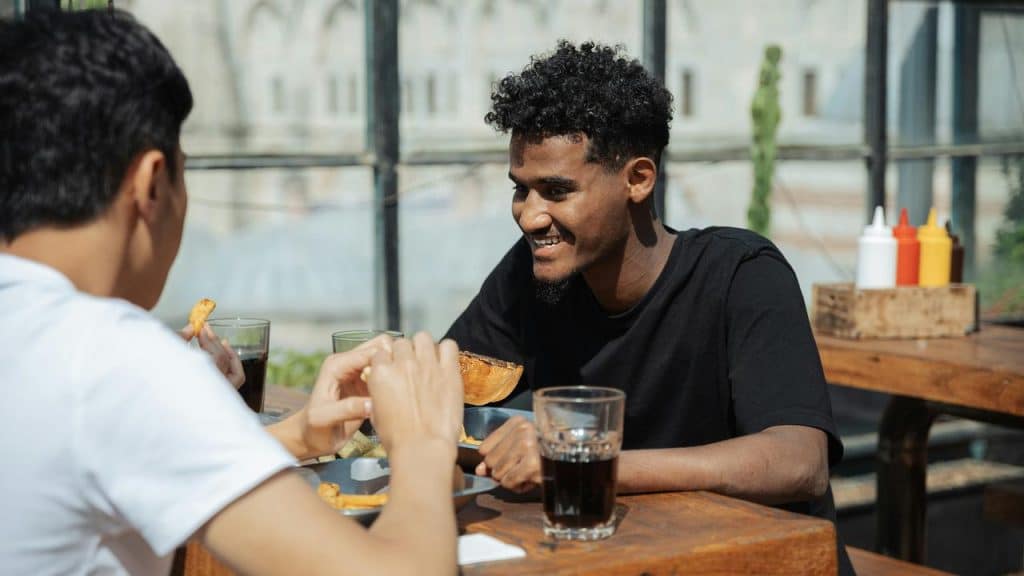 Two Men sitting at a Table eating food.