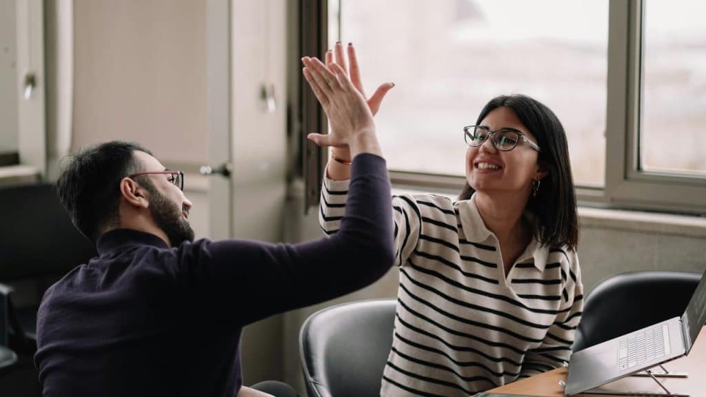A man and a woman high-fiving in an office.