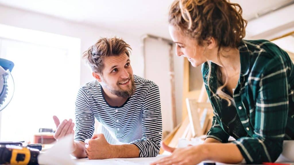 A man and woman reviewing blueprints together in a workshop.