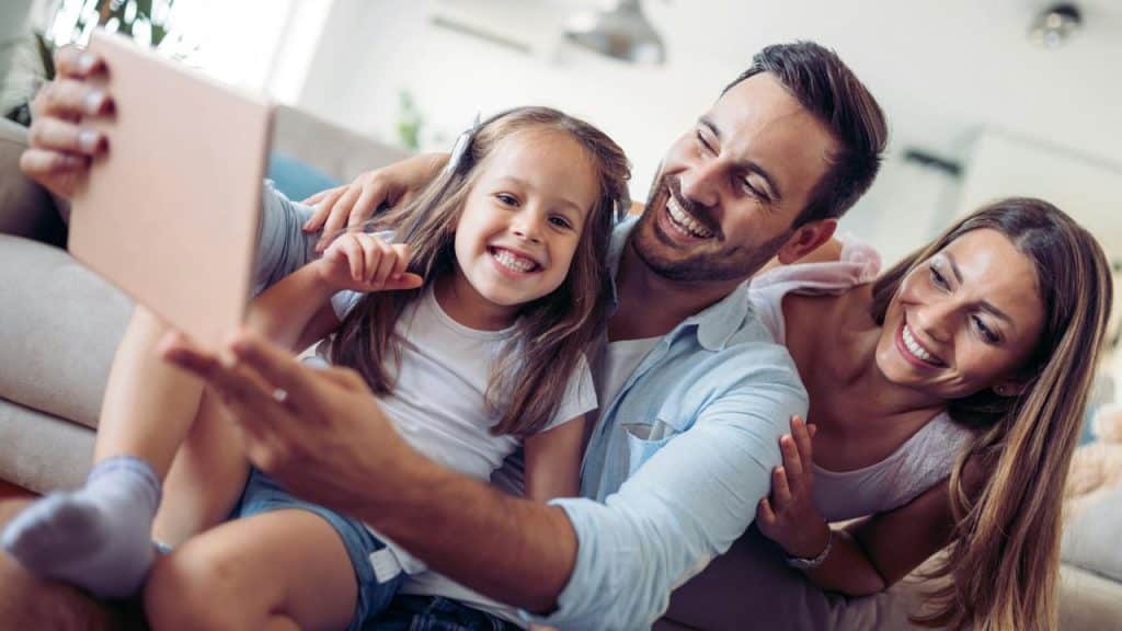 A family taking a happy selfie on their couch.